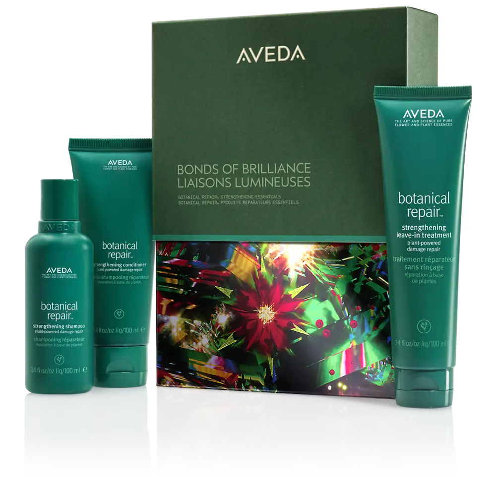 Aveda Bonds of Brilliance gift set features three green bottles of botanical repair hair products, perfect for winter hair care, beautifully displayed with a decorative box in the background. - Jax Salon and Spa