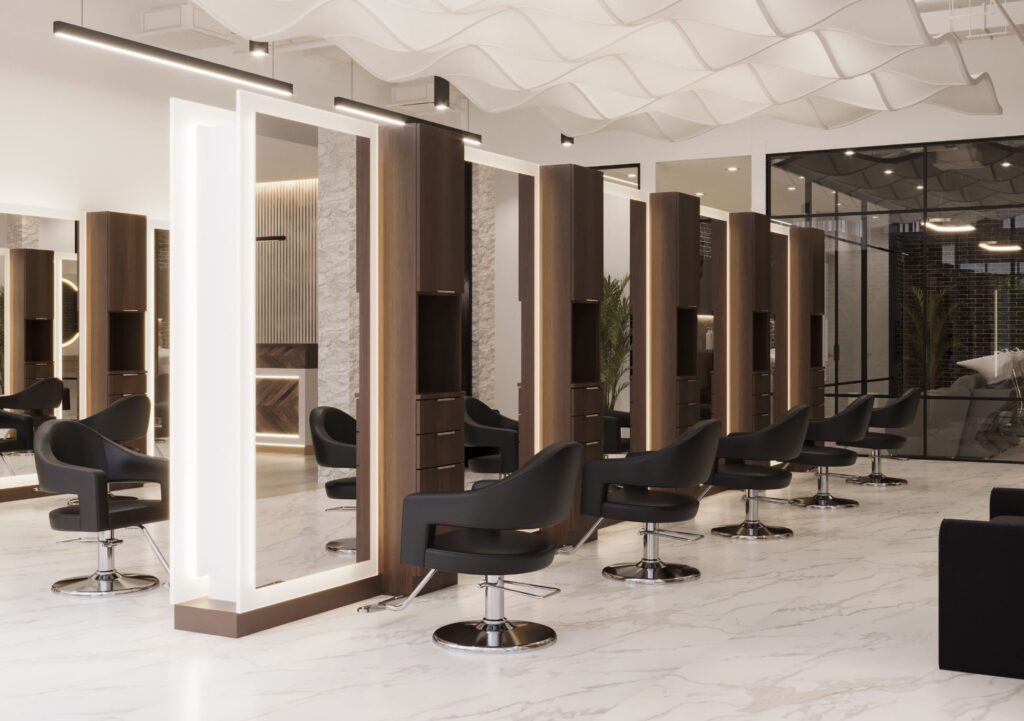 Modern hair salon interior with black styling chairs, large illuminated mirrors, and wood panel dividers on a white marble floor. - Jax Salon and Spa