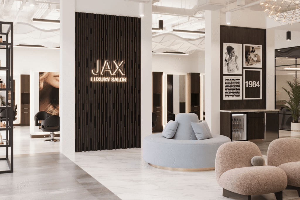 Modern salon interior with a round seating area, salon chairs, wall art, and a sign reading "JAX Luxury Salon" on a dark textured panel. - Jax Salon and Spa
