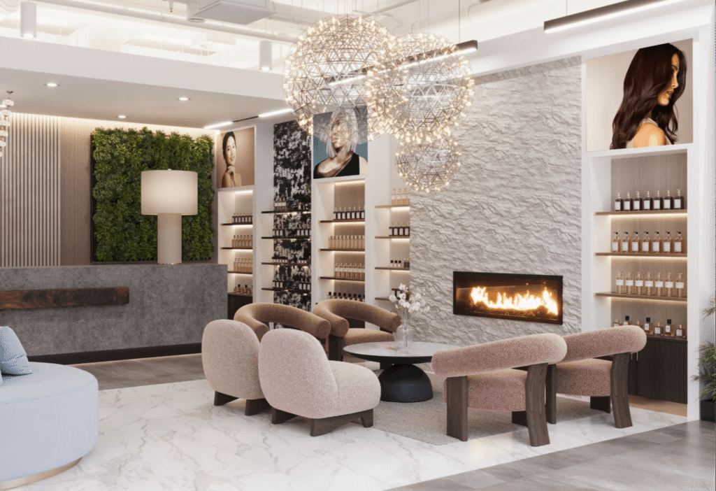 Modern salon lobby with cream lounge chairs, a round coffee table, wall-mounted fireplace, products on shelves, framed portraits, and hanging geometric light fixtures. - Jax Salon and Spa