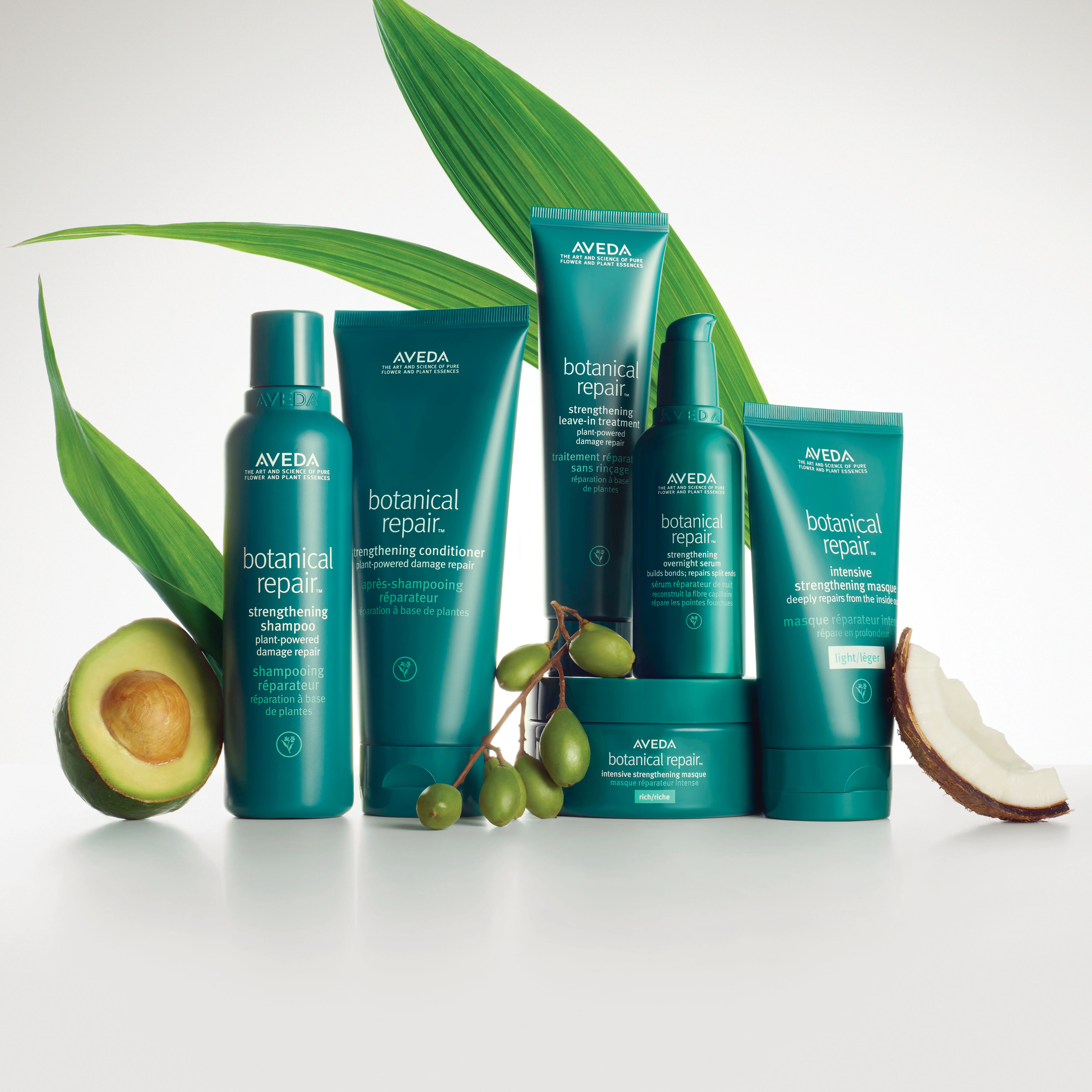 Five Aveda Botanical Repair haircare products are displayed with avocado, coconut, and green leaves on a white background. - Jax Salon and Spa